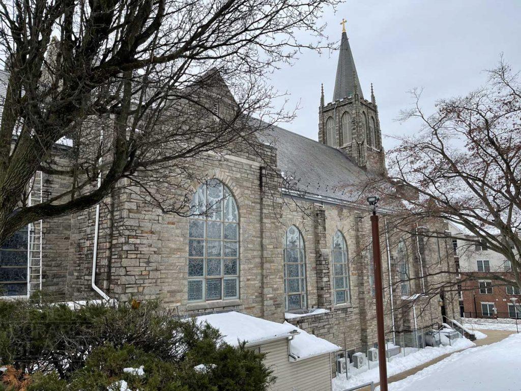 a house covered in snow in front of a church