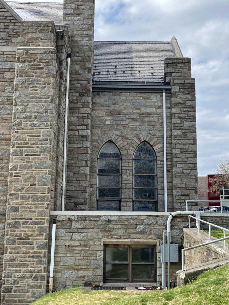 a stone building that has a bench in front of a brick wall