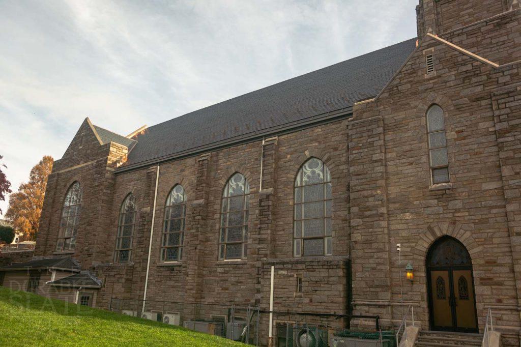 a large brick building with grass in front of a church