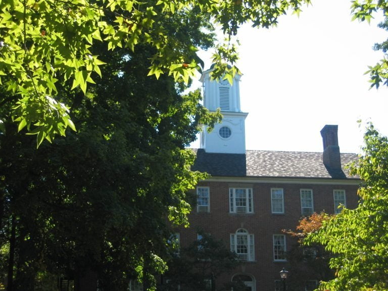 a small clock tower in front of a tree