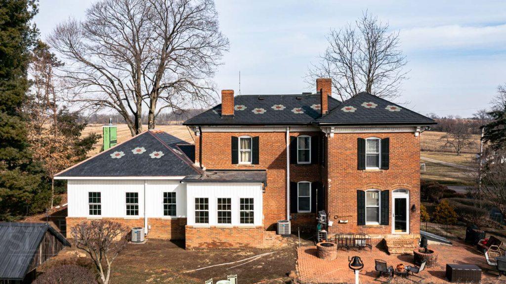 a house with trees in front of a brick building