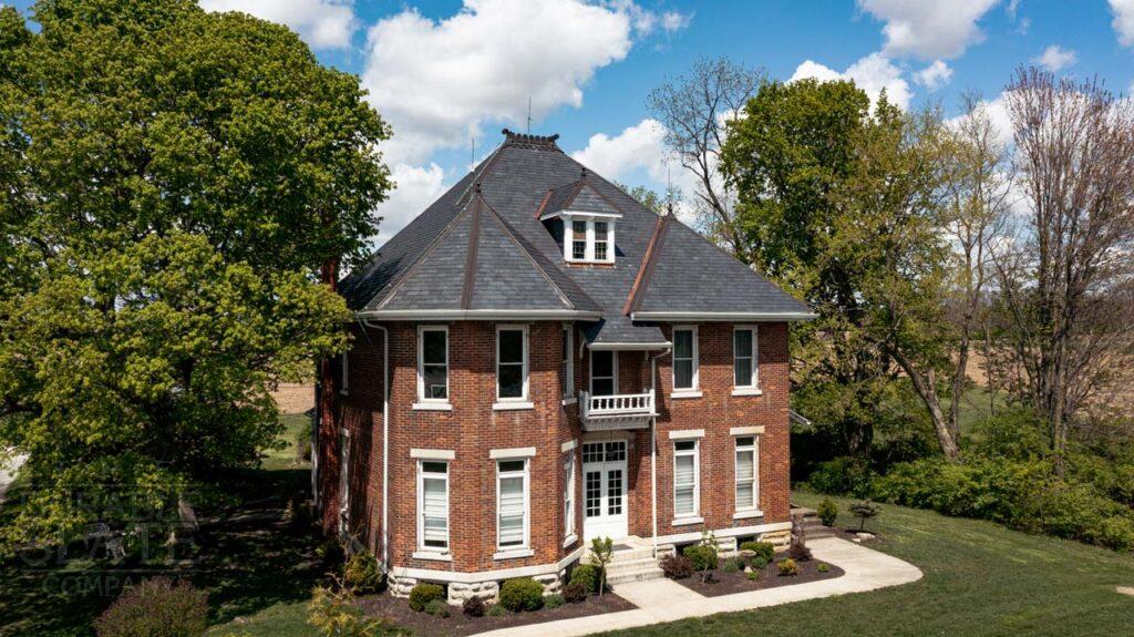 an old brick house with trees in the background