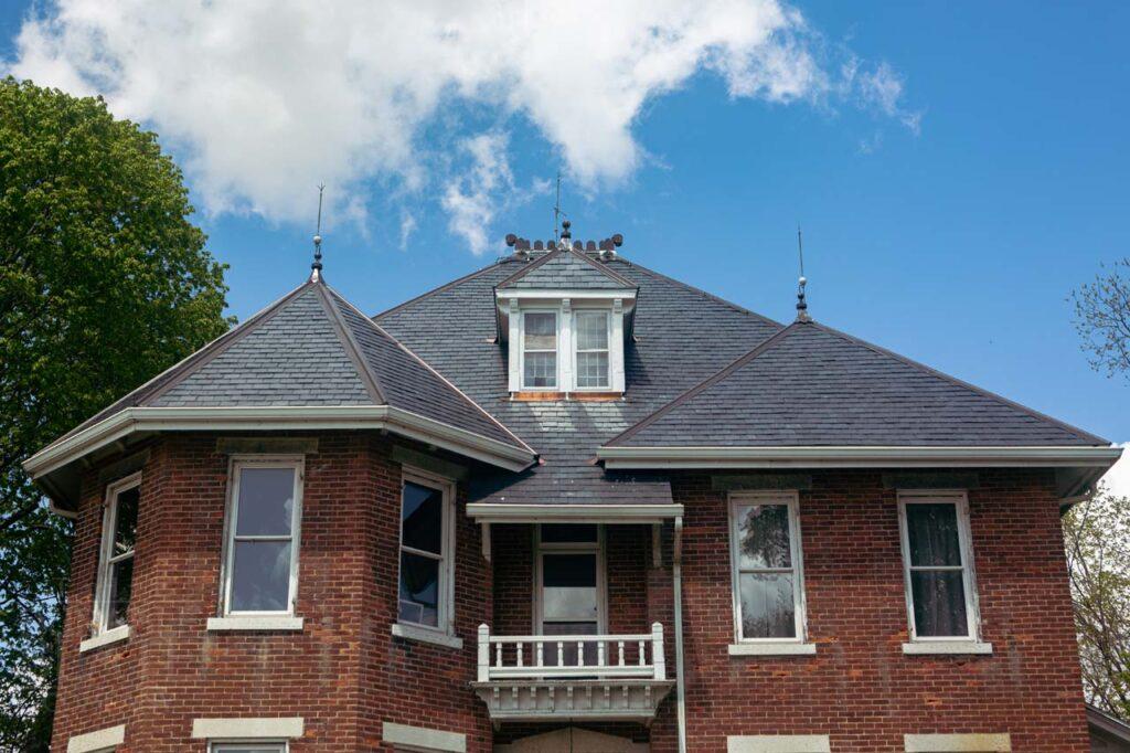 a tall brown brick building next to a house