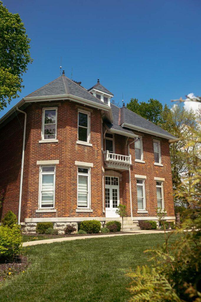 a large brick building with grass in front of a house